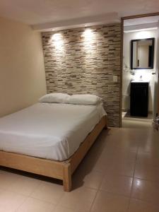 1 dormitorio con cama y pared de ladrillo en Hotel Los Angeles, en Tequesquitengo