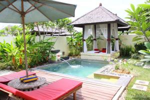 a swimming pool with an umbrella and a gazebo at Kalicaa Villa Resort, Tanjung Lesung in Tanjung Lesung