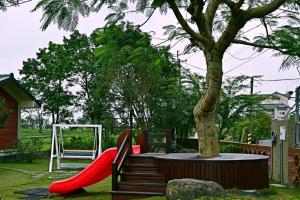 un parque infantil con un tobogán rojo junto a un árbol en Yesday B&B, en Dongshan