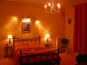 a bedroom with a bed and two lamps and a chandelier at Hôtel le Dauphin in Moulins-la-Marche