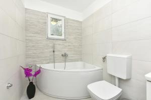 ein Badezimmer mit einer weißen Badewanne und einem WC in der Unterkunft Apartman Kresan in Sukošan + 22 Fotos