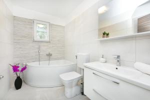 ein weißes Badezimmer mit einer Badewanne, einem WC und einem Waschbecken in der Unterkunft Apartman Kresan in Sukošan