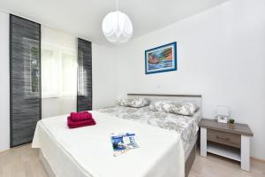 ein weißes Schlafzimmer mit einem Bett und einem Tisch in der Unterkunft Apartman Kresan in Sukošan