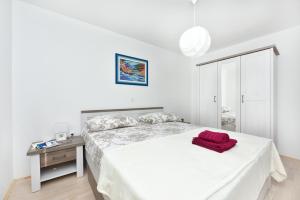 ein weißes Schlafzimmer mit einem Bett mit einem roten Objekt darauf in der Unterkunft Apartman Kresan in Sukošan
