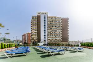 a row of blue lounge chairs in front of a hotel at Hotel Maya Alicante in Alicante