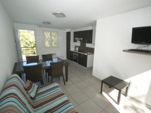 a living room with a table and chairs and a kitchen at Comfy Apartment in Cervione with Swimming Pool in San-Nicolao