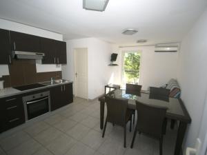 una cucina con tavolo e sedie e una cucina con piano cottura di Comfy Apartment in Cervione with Swimming Pool a San-Nicolao