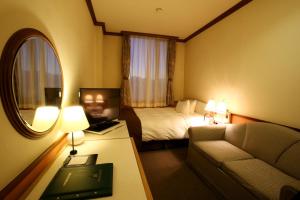 平塚市にあるホテルサンライフガーデンのベッド、ソファ、鏡が備わるホテルルームです。
