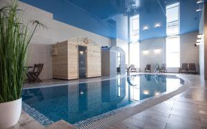 a large swimming pool in a building with chairs and tables at SanMari in Daugavpils