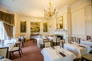 a restaurant with white tables and chairs and a chandelier at The Upper House in Stoke on Trent