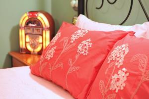 ein Bett mit zwei roten Kissen und einer Uhr in der Unterkunft Belgrave Bed and Breakfast in Belgrave