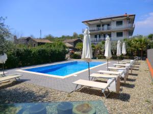 Valley-View Holiday Home in Santa Venerina with Private Pool في سانتا فينيرينا: مسبح مع كراسي جلوس ومظلات بجانب مبنى