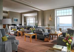 een grote woonkamer met banken, tafels en ramen bij Dunmore House Hotel in Clonakilty