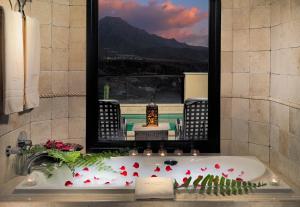 a bathroom with a bath tub with red flowers and a mirror at Royal Garden Villas, Luxury Hotel in Adeje