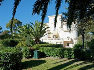 サン・ラファエルにあるApartment in villa with pool and beach accessのヤシの木や茂みのある白い大きな建物