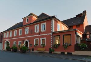 un bâtiment rouge avec un banc devant lui dans l'établissement Hotel Grüner Baum, à Pommersfelden