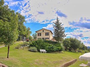 una casa y un parque con un banco en un patio en Serene Holiday Home in Piticchio with pool and scenic views en Arcevia