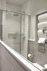 a bathroom with a shower and a toilet and towels at The Clerk & Well Pub and Rooms in London