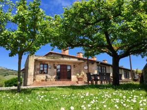 una antigua casa de piedra con árboles y flores en Posada La Roblera, en Oreña