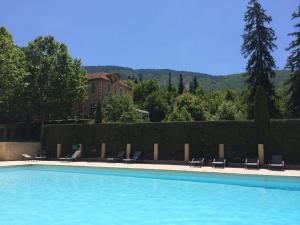 a swimming pool with chairs and a house in the background at Château Luxury Stay Montbrun in Montbrun-les-Bains