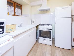 a white kitchen with white appliances and wooden floors at Former farmhouse fully renovated with garden near the Auvergne volcanoes in Calvinet