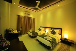 a hotel room with two beds and a ceiling fan at Ruins Chaaya Hotel in Polonnaruwa