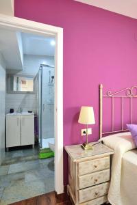 Habitación de color rosa con cama y baño. en De Patios, en Córdoba