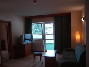a living room with a couch and a tv and a window at Hotel Seasons in Tryavna