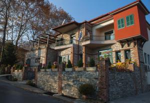 a brick house with potted plants on a wall at Evzin Hotel in Kato Loutraki