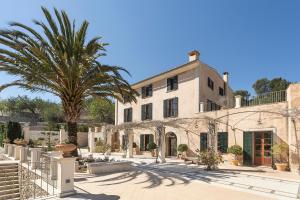 a large building with a palm tree in front of it at Majestic Holiday Estate in Calvià Up to 12 Guests in Calvia Town