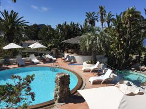 una piscina en un complejo con sillas y sombrillas en Paco Residence Benessere & Relax, en Isquia