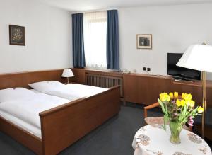 PommersfeldenにあるHotel Grüner Baumのベッド2台、テーブル(花付)が備わる客室です。