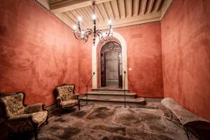 a hallway with red walls and a chandelier and chairs at Palazzo Petrella in Cortona