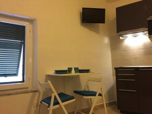 cocina con 2 sillas, mesa y barra en Monolocale Minzoni en Porto Azzurro