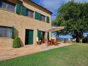 um pátio com uma mesa e um guarda-chuva em frente a um edifício em Luxurious Cottage with Swimming Pool in Montelabbate em Montelabbate