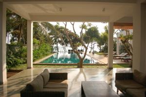 a living room with a view of a swimming pool at Roman Beach Hotel in Hikkaduwa