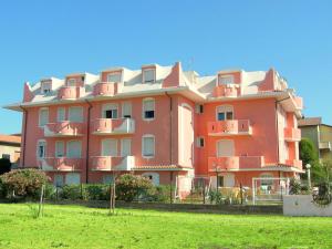ポルト・ガリバルディにあるBelvilla by OYO Porto Garibaldi Trilo Doriaの芝生の上にバルコニー付きの大きなピンクの建物