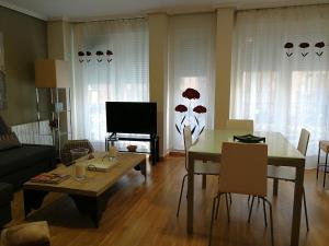 sala de estar con mesa, sillas y TV en 18 Torres El Pilar en Zaragoza