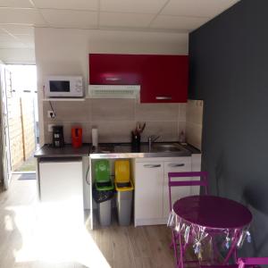 a small kitchen with red cabinets and a purple stool at Le Bas de Cilaos in Cilaos