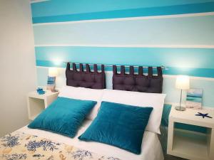 a bedroom with a bed with two blue pillows at Acquamarina Apartment with Terrace in Marsala
