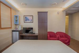 Empire Hotel في تايبيه: غرفة مع سرير ومكتب مع كرسي احمر