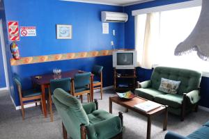 uma sala de estar com paredes azuis e uma mesa e cadeiras em Atlantis Backpackers em Picton
