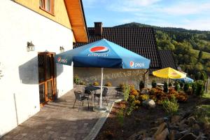 a patio with a blue umbrella and chairs at Domki Oberwanka in Mszana Dolna