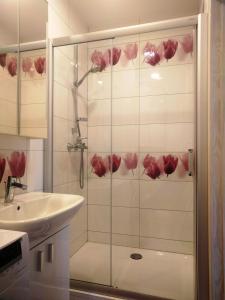 La salle de bains est pourvue d'une douche avec des roses sur le mur. dans l'établissement Apartamentai Gertrūda, à Druskininkai