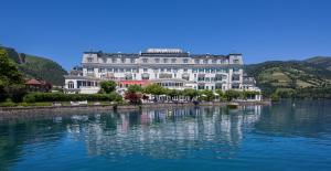 a large white building sitting on top of a lake at Grand Hotel Zell am See in Zell am See