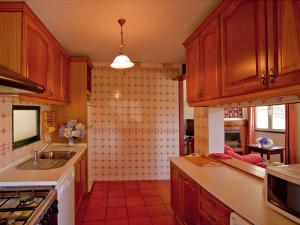 cocina con armarios de madera, fregadero y encimera en Quinta Das Colmeias Cottage en Santo da Serra