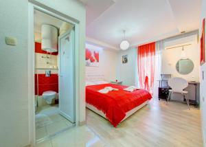 a bedroom with a red bed and a bathroom at Pansion Glory in Međugorje