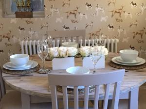 una mesa de madera con sillas, platos y copas de vino en Scalby Grove Cottage, en Scarborough