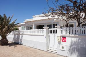 ein weißes Haus mit einem weißen Zaun und einem Baum in der Unterkunft Villa Mela in Playa Honda