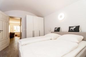 two beds in a white bedroom with white cabinets at Palace am See in Tegernsee
